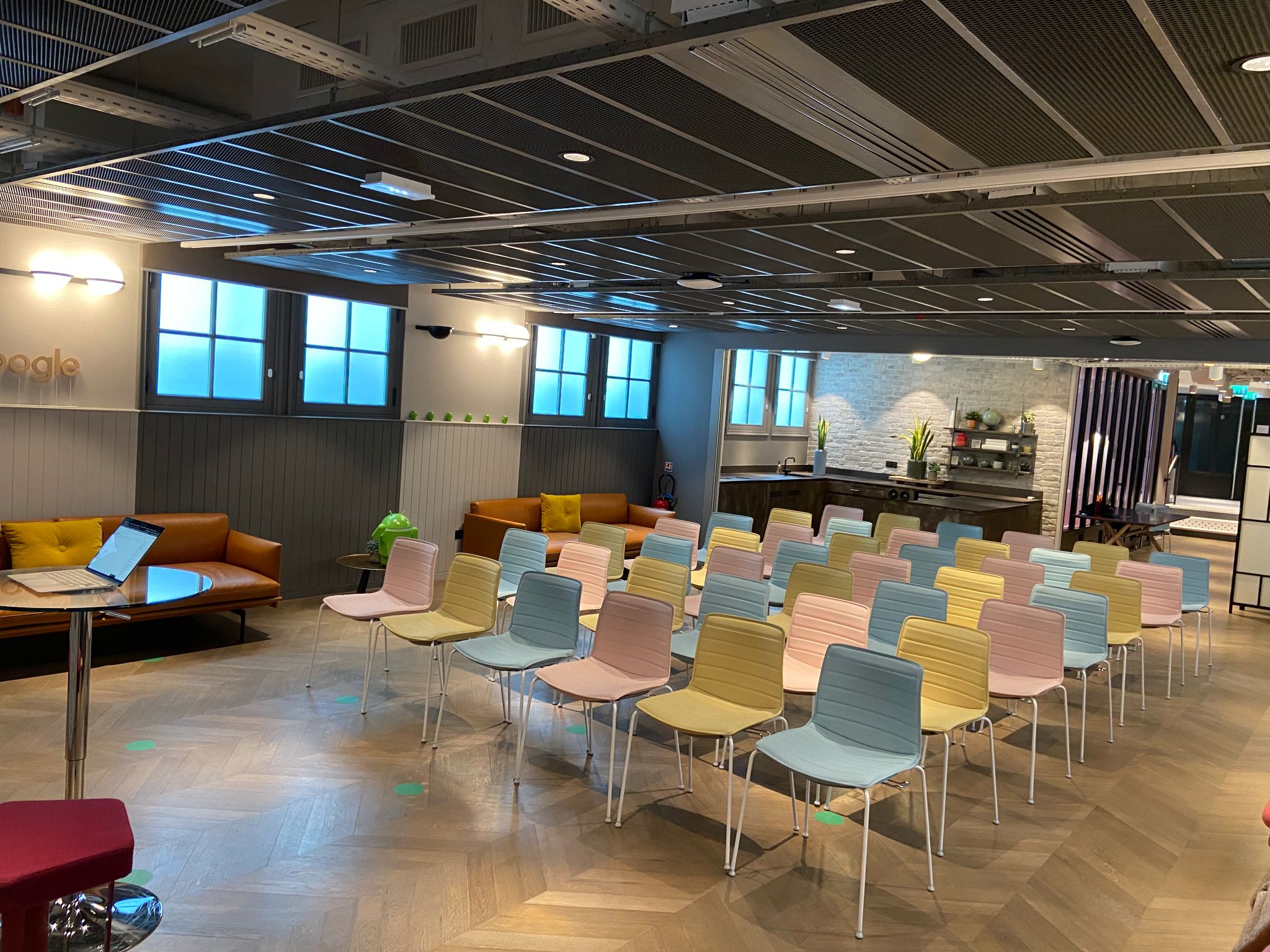 Chatelet breakout room with pastel chairs in theater rows, brick walls, and warm wood floors.